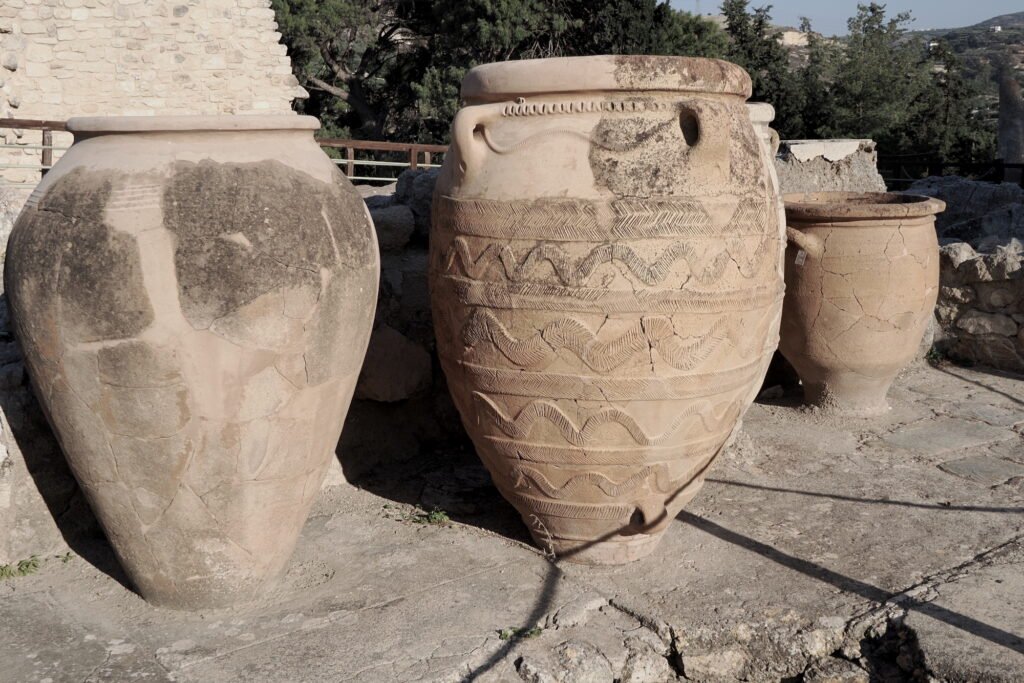 Ancient Minoan pots made of reddish-brown clay, showing hand-molded and uneven shapes with a rustic weathered texture.