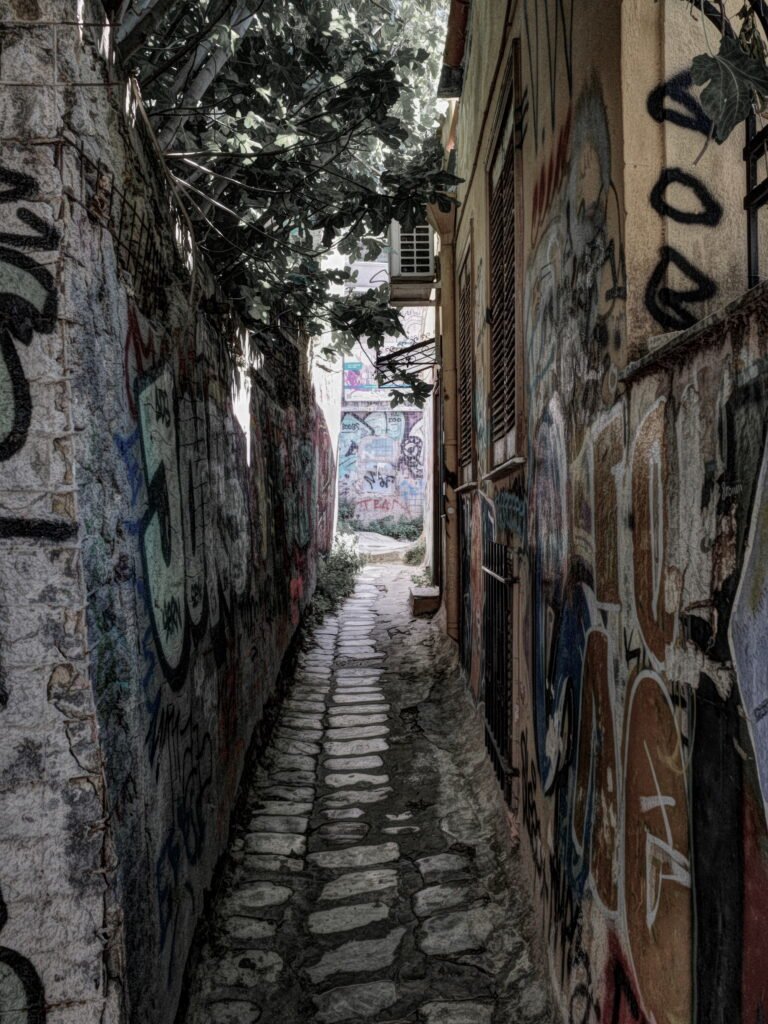 A narrow alley in Anafirotika with well worn stone steps and stone walls covered with graffiti.