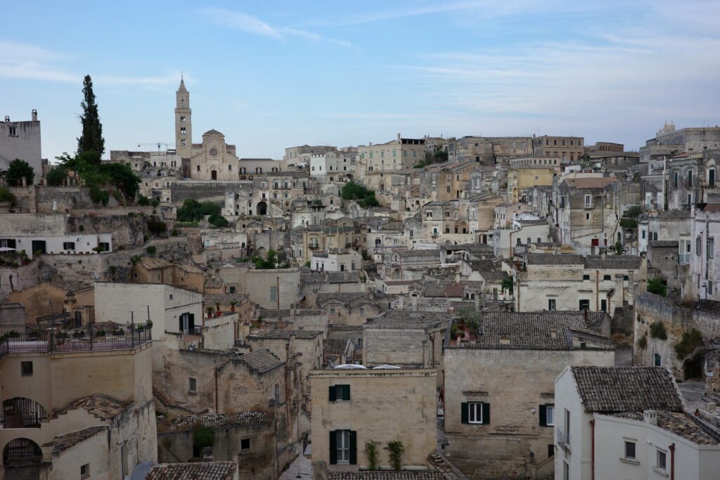 A scenic view of the Sassi di Matera of the Stone City of Matera with tightly packed homes built into the mountainside. The homes are old and weathered and the essence of wabi-sabi.