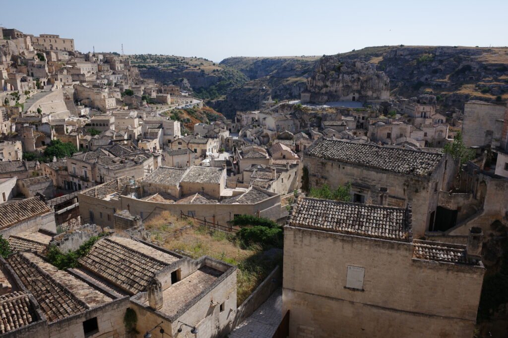 A view looking out on the Sassi di Matera with haphazard alleys, homes built into the mountain walls, and terra-cotta tiled roofs.